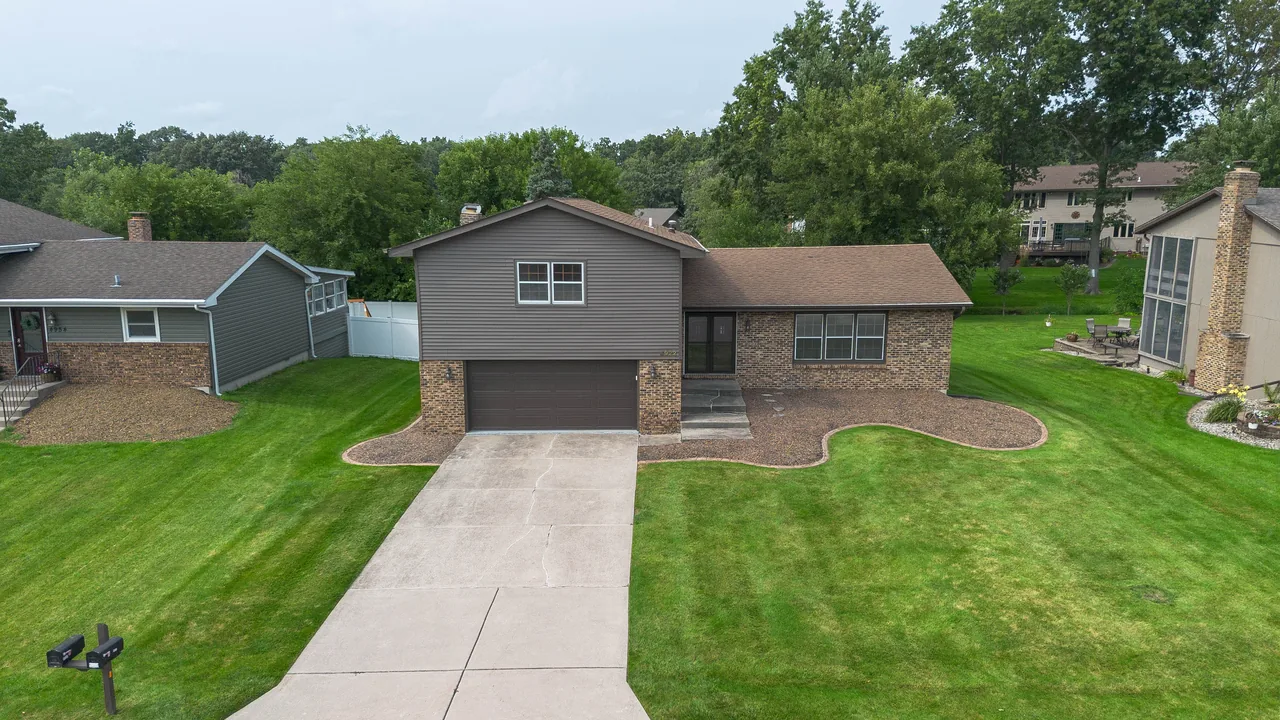 Aerial view looking down on a split-level home's front elevation, driveway and manicured lawn