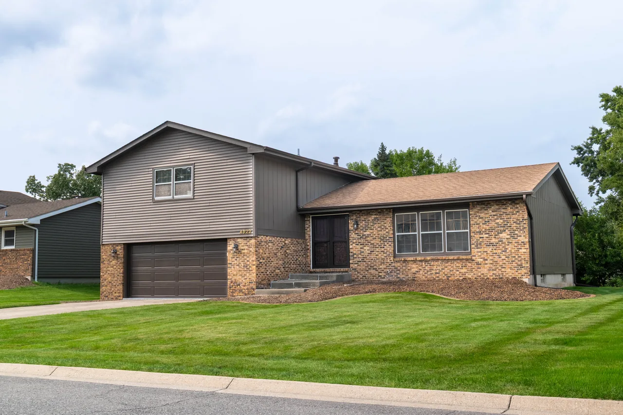 Brick and siding split-level home photographed from a front three-quarter angle on a bright day