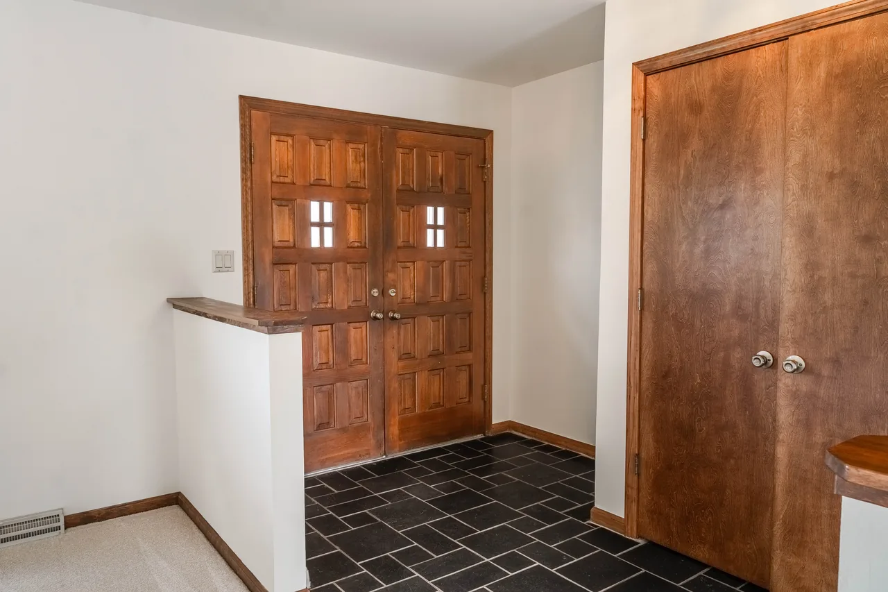 Entry foyer with solid wood double doors and dark slate tile flooring