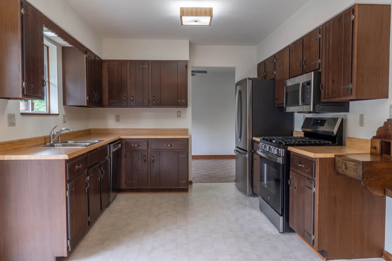 Kitchen with dark wood cabinetry, stainless steel range and light countertops