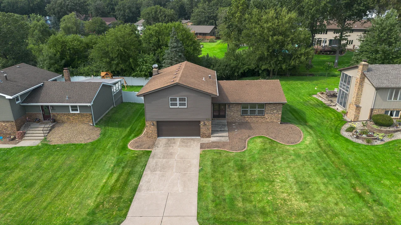 Aerial three-quarter view of the property and neighbouring homes among mature trees