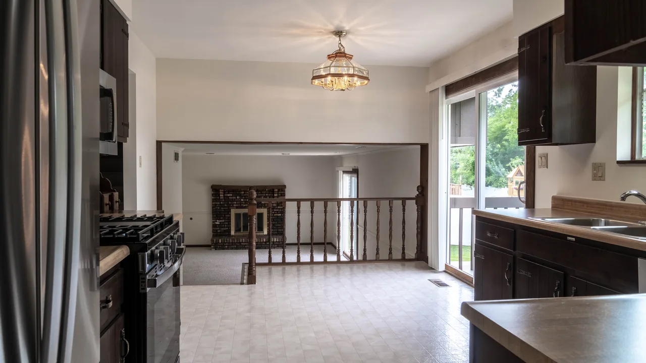 View from the kitchen through to the living room with a sliding door letting in daylight