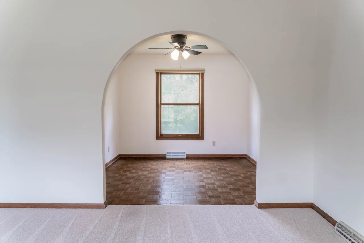 Arched opening leading through to a dining nook with a ceiling fan and window